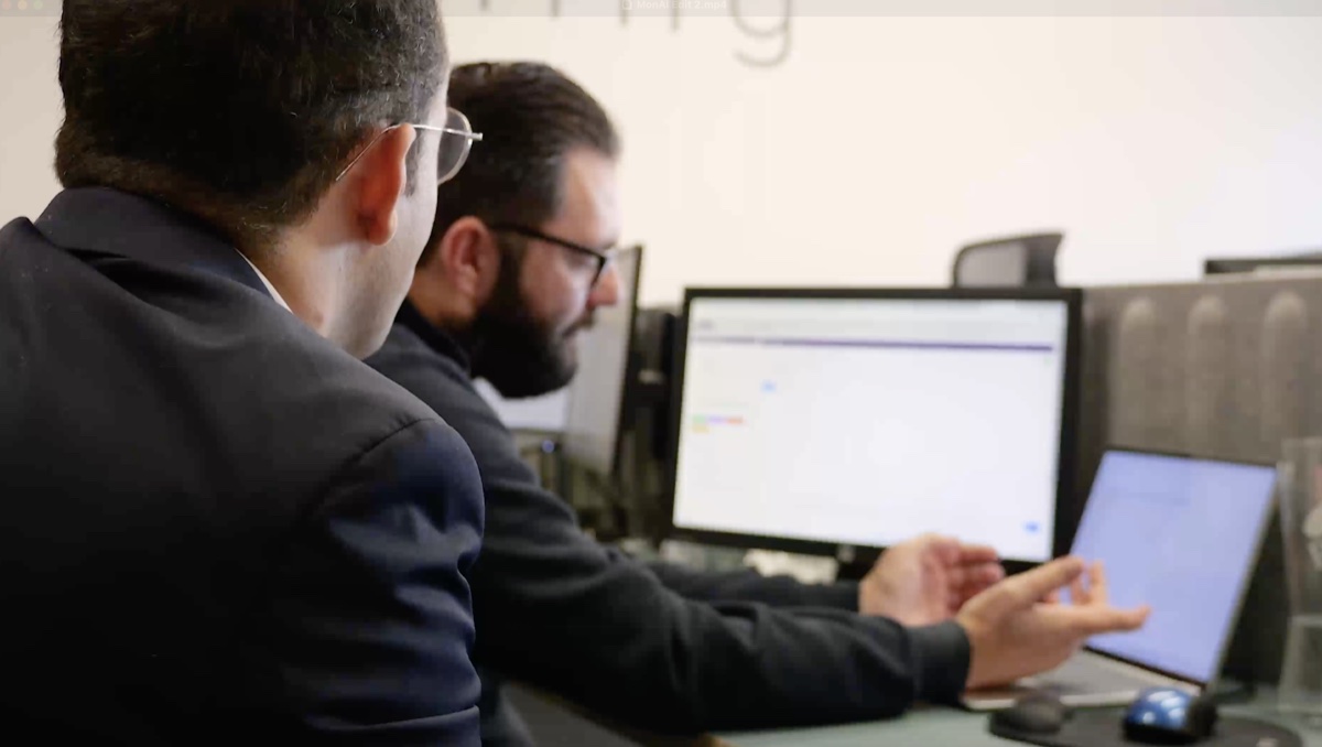UK financial advisors comparing pension transfer software solutions on dual monitor setup in professional office environment
